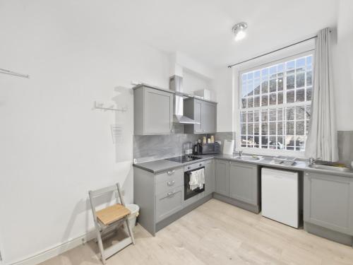 a kitchen with gray cabinets and a window at Room for 5 in Zone 2 - Willesden Green in London