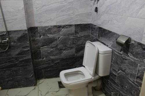 a bathroom with a toilet in a black tiled wall at فندق النادي in Aswan