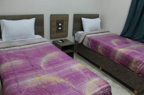 two beds in a room with purple blankets at فندق النادي in Aswan