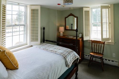 a bedroom with a bed and a mirror and a chair at The Historic General Stanton Inn in Charlestown