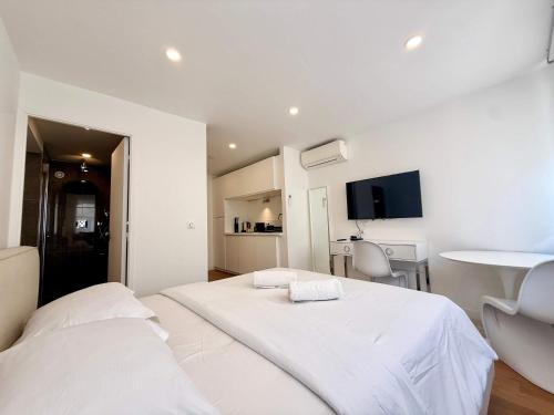 a white room with two beds and a table at B044 Studio moderne Croisette 100m in Cannes