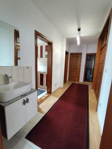 a bathroom with a sink and a red rug at White Apartment in Prizren