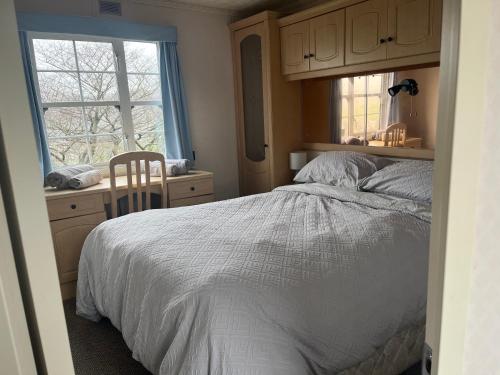 a bedroom with a bed and a desk and a window at Bridge Farm Caravan in Buxton