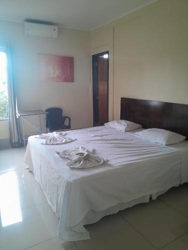 a bedroom with a large white bed with white sheets at Hotel Pousada das Palmeiras in Colíder
