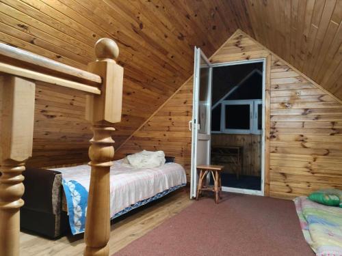 a bedroom in a log cabin with a bed and a tv at Калина in Deneshi