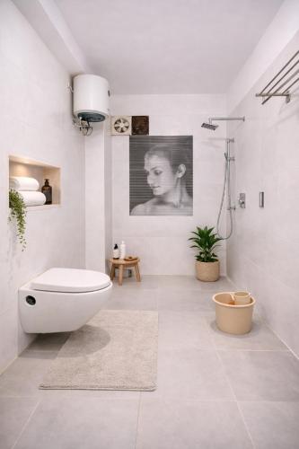 a white bathroom with a toilet and a plant at Hotel Nomadic in Udaipur
