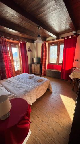 a bedroom with a large bed with red curtains at Maison Mariot in Roure Turin