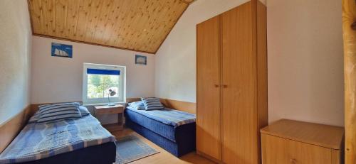 a small bedroom with two beds and a window at Barwy Morza - domki in Rowy
