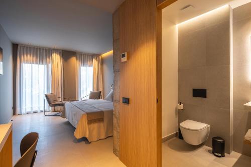a hotel room with a bed and a toilet at The Alma Suite in Alora