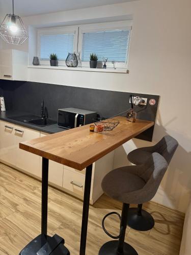 a kitchen with a wooden table and a chair at Prestige Suite DS in Dunajská Streda