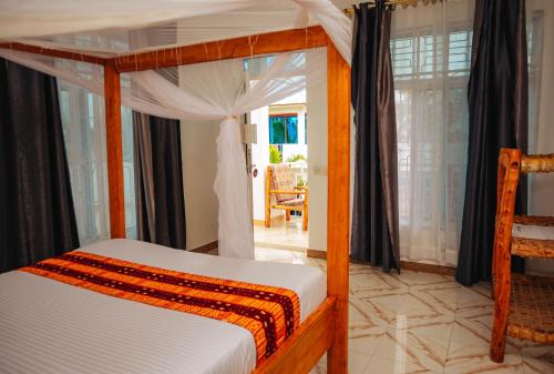 a bedroom with a canopy bed and a dining room at Karibu House Paje in Paje