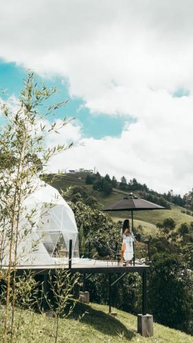 a woman sitting on a table with an umbrella at Ecohotel Monte Tierra Habitaciones y Glamping in Filandia
