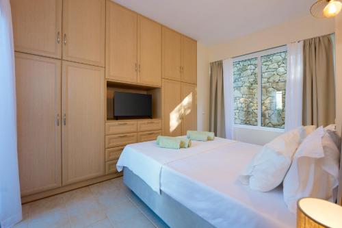 a bedroom with a white bed and a television at Fereniki's place in Gaios