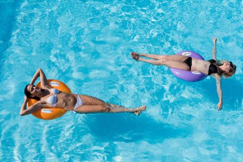 Due donne che galleggiano in una piscina in acqua di Olimpia Hotel & Aparthotel a Bibione