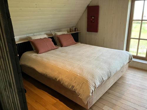 a bedroom with a large bed with pink pillows at Rust en natuur in de Vlaamse Ardennen in Kluisbergen