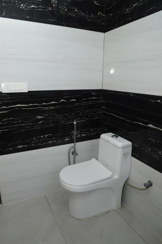 a white toilet in a bathroom with black walls at Aashray in Dehradun