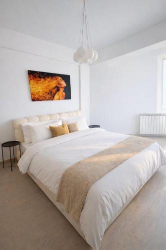 a white bedroom with a large bed with white walls at Apartament Meraki SeaView in Mamaia Sat/Năvodari