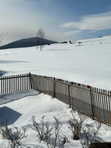 a fence covered in snow with a snow covered field at Apartmán Amálka in Ktiš