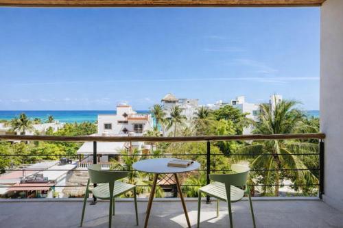 a balcony with a table and chairs and the ocean at Lalola DownTown Boutique Apartments in Puerto Morelos