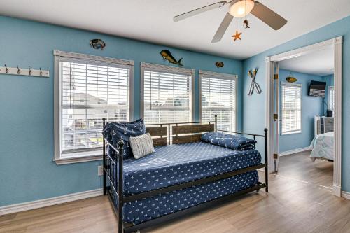 a bedroom with blue walls and a bed with a ceiling fan at 1 Block to Surfside Beach: Home w/ Deck! in Freeport