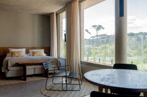 a bedroom with a bed and a table and a large window at CasaChica Hotel in José Ignacio