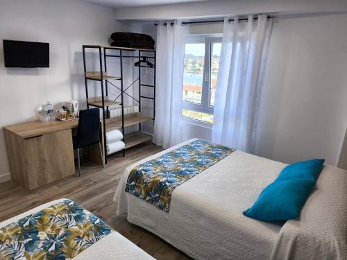 a bedroom with two beds and a desk and a window at Hostería VISTAPARK in El Astillero