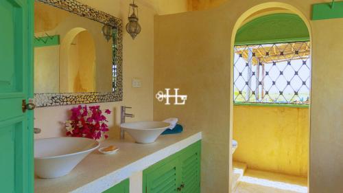 a bathroom with two sinks and a window at Kavunjeni Villa in Uyombo
