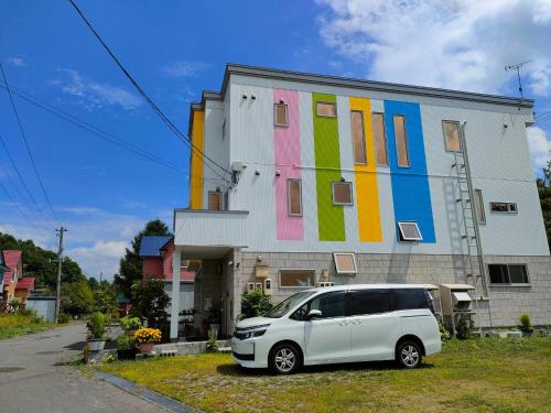 a white van parked in front of a building with a colorful building at Hokkaido Hakodate Onuma National Park Kenzo's House in Ōnuma