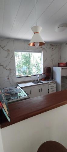 a kitchen with a counter and a sink and a window at Chalé da Helô in Nova Friburgo