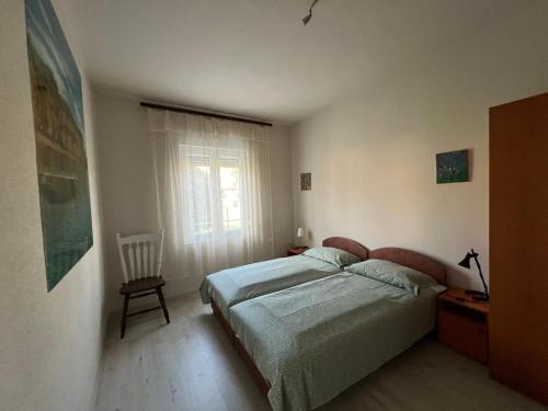 a bedroom with a bed and a chair and a window at Lukács nyaralóház in Balatonfenyves