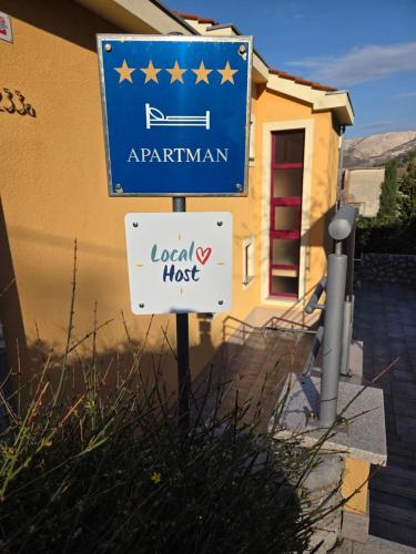 a sign for a local house in front of a building at Apartment Smokvina in Punat