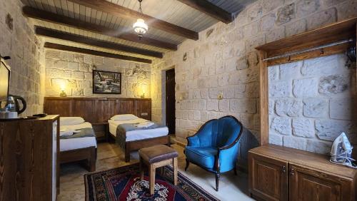 a room with two beds and a blue chair at Yıldız Hotel in Ürgüp