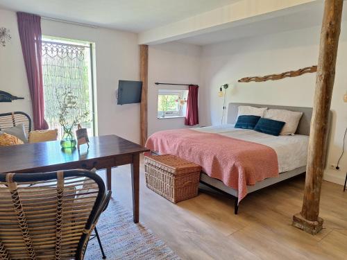 a bedroom with a bed and a desk and a table at Kade10Buren in Buren