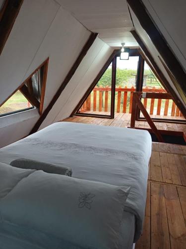 a bed in the attic of a room with windows at Stush In the Bush in Stegi