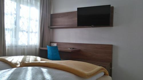 a bedroom with a bed and a tv on the wall at Pension Elisabeth - Rooms & Apartments in Salzburg