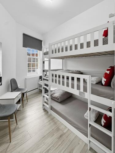 a dorm room with two bunk beds and a desk at Trio Den in Zone 2 - Willesden Green in London