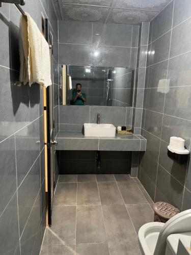 a man taking a picture of a bathroom with a sink at Khách Sạn 68 Trần Đề in Ấp Nhà Việc