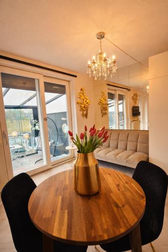 a living room with a wooden table with a vase of flowers at Amberdi Apartment Amsterdam Schiphol Airport in Hoofddorp