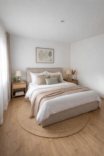 a white bedroom with a large bed and two tables at Appartement et spa in Douai