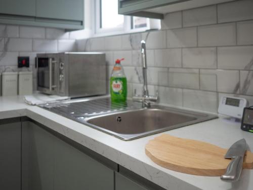 a kitchen counter with a sink and a bottle of soda at Spacious 2-Bedroom Flat in Worcester Park