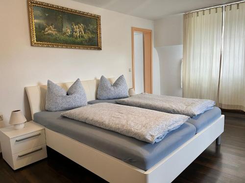 a bed with two pillows and a painting on the wall at Gasthaus Adler Weilheim, Waldshut in Weilheim
