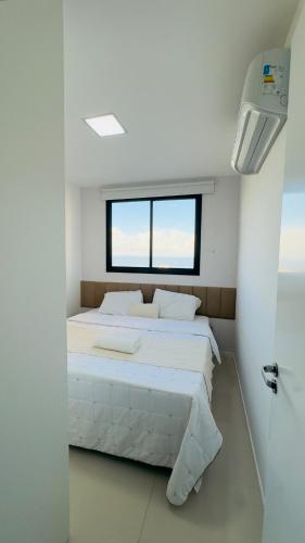a bedroom with a large white bed with a window at Seu refúgio com vista para o mar in Vila Velha