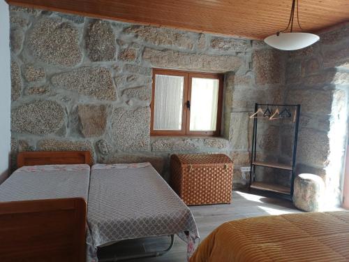 a bedroom with two beds and a stone wall at Casa da Fragoeira in Gandarela