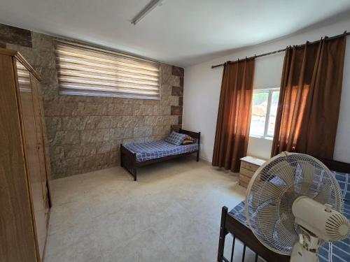 a living room with a bed and a fan at بيت اطلالة الوادي in Ajloun