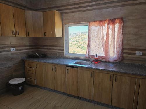 a kitchen with a sink and a window at بيت اطلالة الوادي in Ajloun
