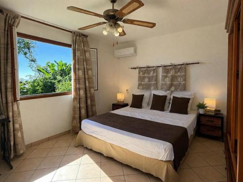 a bedroom with a bed with a ceiling fan and a window at La caza papangues in Sainte-Suzanne