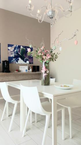 a white dining room table with white chairs and a vase of flowers at Il colore dei sogni in Due Carrare