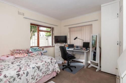 a bedroom with a bed and a desk with a computer at Sunset Nest in Meadowridge