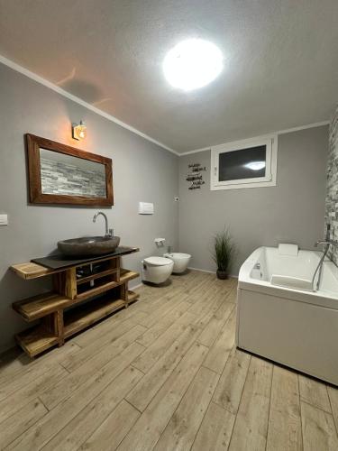 a bathroom with a tub and a sink and two toilets at Villa Bocciolo, piscina, giardino, vasca idromassaggio in Manerba del Garda