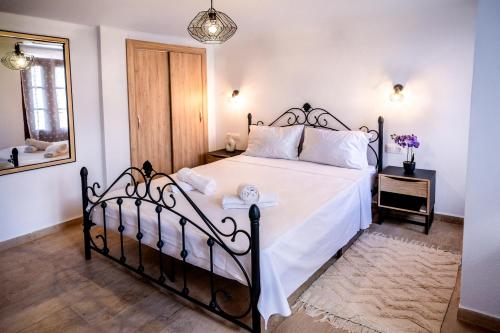 a bedroom with a bed with white sheets and a mirror at White Lotus in Próti